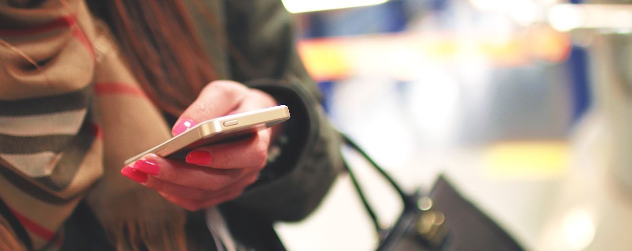 Close-up of a hand holding a smartphone. The user is likely using instant messaging (IM) services, which have become wildly popular with the boom in mobile technology.