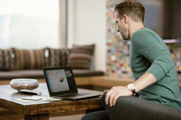 Young man working from home on his laptop. He is using collaboration tools to teleconnect with the home office, a current trend in business culture.