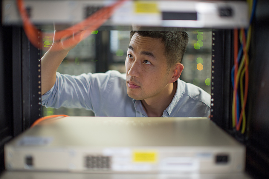 Man studying the server of his computer network, likely contemplating the difficulties of IT Infrastructure